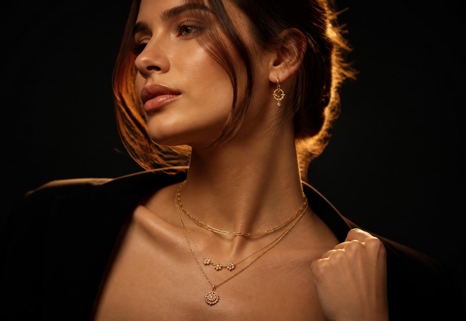Model wearing layered gold necklaces and gold earrings